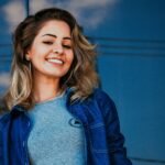Portrait of a smiling young woman outdoors with a blue sky background.